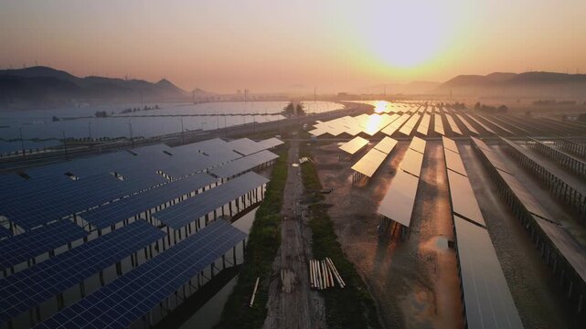 Large-scale photovoltaic power station array landscape at sunrise with solar panels reflecting golden light