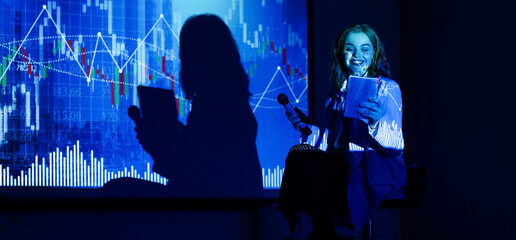 Female business speaker with tablet computer conducting seminar in dark office