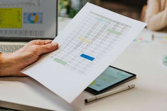 Businessman analyzing chart data at office desk with close up hand