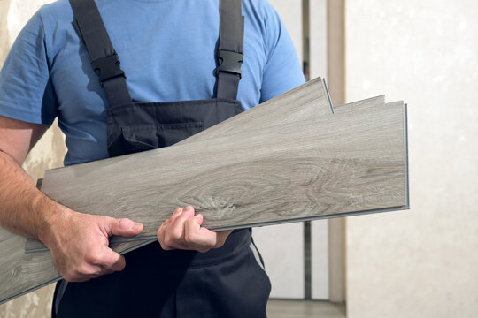 Worker holding vinyl plank flooring for home renovation