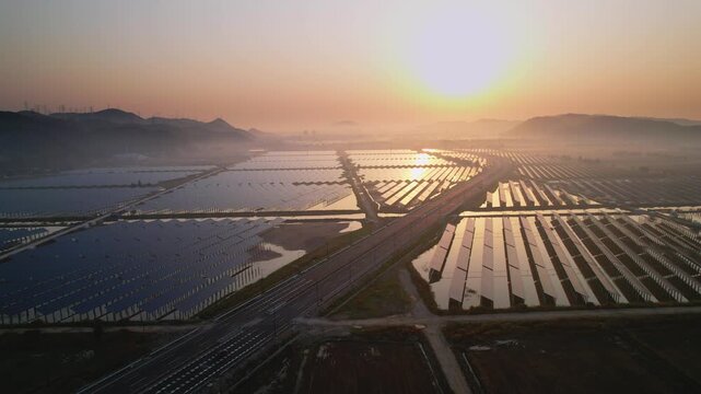 Solar power plant and highway intersecting at sunset with mountainous backdrop and water reflections