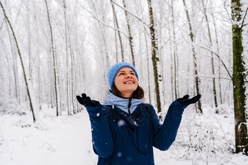 Happy woman enjoying winter snowfall outdoors