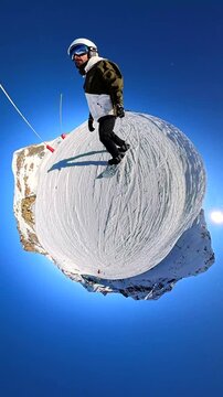 Young man snowboarding down a snowy mountain on a sunny day with a clear blue sky, filmed with a 360 degree camera creating a surreal tiny planet effect for an extreme sports concept