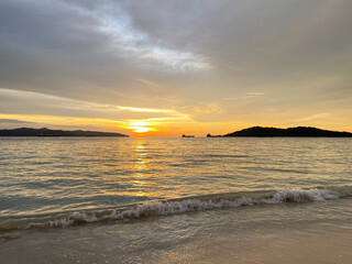 Golden sunset reflecting on calm sea with gentle waves, peaceful coastal evening atmosphere