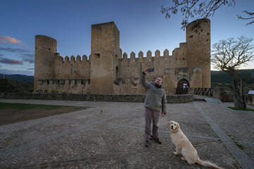 Man taking a selfie with his Golden Retriever dog at medieval Frias castle in Burgos Spain at sunset