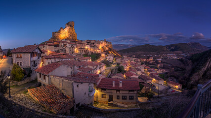 Illuminated medieval village of Frias at twilight with castle on rock in Burgos Spain