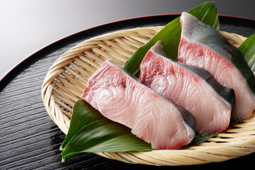 ざるに盛ったぶりの切り身（葉蘭・黒背景）