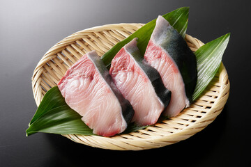 ざるに盛ったぶりの切り身（葉蘭・黒背景）