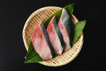 ざるに盛ったぶりの切り身（葉蘭・黒背景）