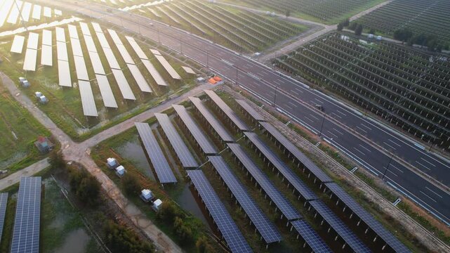 Aerial view of a large-scale photovoltaic power station adjacent to a highway