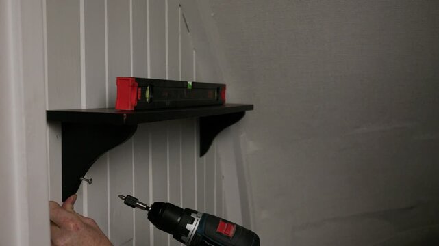 Carefully drilling wall shelf bracket into place