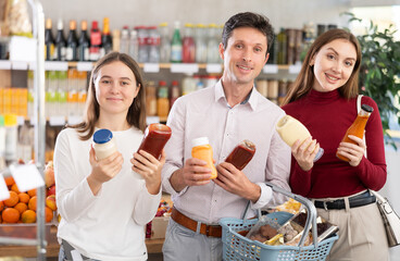 In healthy eating store, positive family of customers chooses sauce and actively argues about...