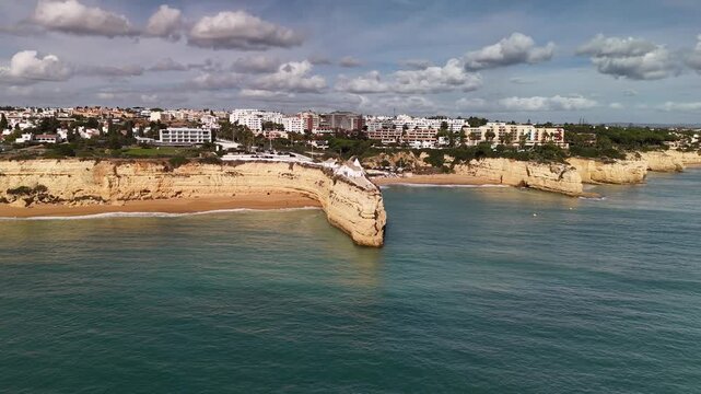 Low Altitude Aerial Orbit Around the Historic White Chapel of Nossa Senhora da Rocha Perched on a Rocky Peninsula in Algarve Portugal