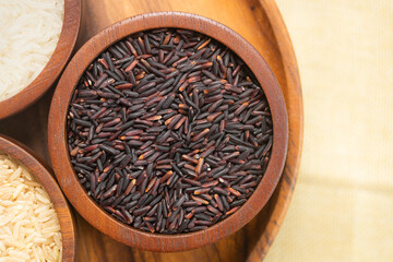 Top view of purple riceberry rice grains in a wooden bowl. Thai food