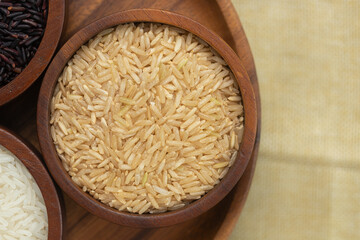 Top view of brown rice grains in brown wooden bowl. Thai food