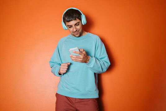 Person in blue sweatshirt with headphones listening to music on phone