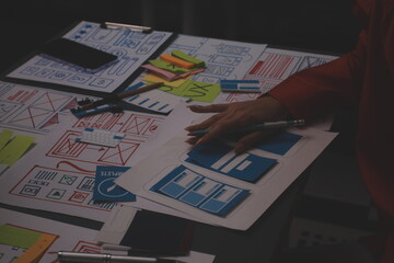 Team of uxui designers pointing at computer screen, discussing new mobile app design in the office