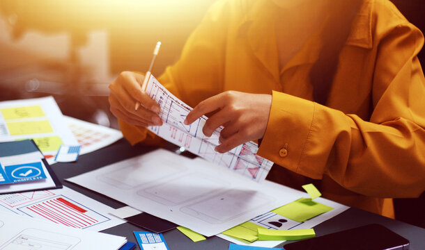 Team of uxui designers pointing at computer screen, discussing new mobile app design in the office - Powered by Adobe