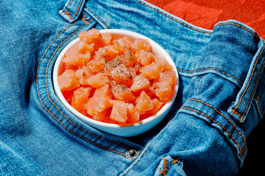 Bowl of smoked marinated diced salmon on crisp denim background