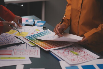 Team of uxui designers pointing at computer screen, discussing new mobile app design in the office