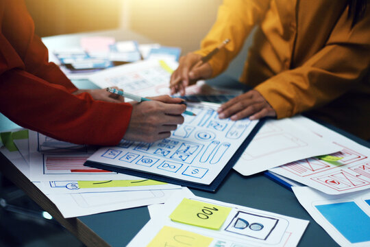 Team of uxui designers pointing at computer screen, discussing new mobile app design in the office - Powered by Adobe