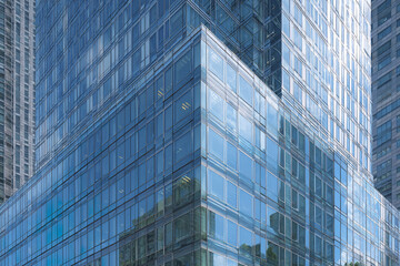 Modern glass office building with reflective blue windows in urban city center, showcasing contemporary architecture and clean lines under daylight sky