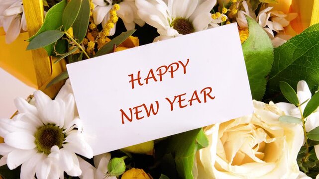 A lovely display of radiant blossoms including roses and daisies surrounds a greeting card that sweetly wishes Happy New Year. It conveys love and joyous sentiments