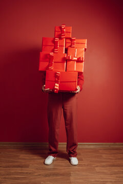 Person in red holding stacked presents against a red monochrome wall