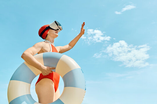 Woman in retro swimsuit with VR headset and swimming ring under a dramatic sky