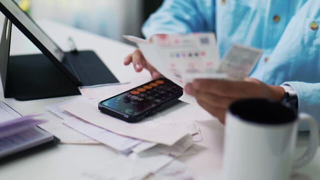 Asian Man Using Smartphone while Working at Desk in Home Office.