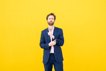 Confident businessman in blue suit against yellow background