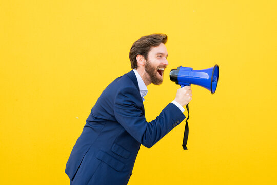 Businessman yelling into megaphone on yellow background