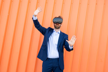 Businessman wearing VR glasses gesturing against orange background