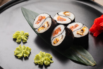 Yin yang sushi rolls with eel and salmon served on a black plate with wasabi and ginger © Hihitetlin