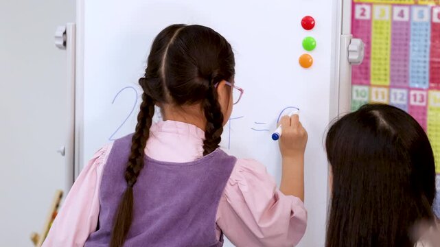 Elementary Student Solving Math Equation on Classroom Whiteboard