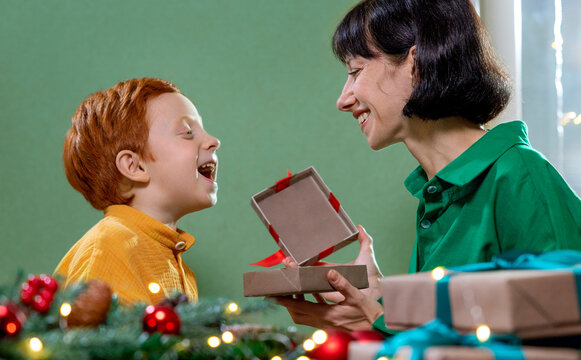 Mother and son happily opening Christmas gift together at home