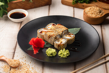Fried sushi rolls with fish cream cheese and rice topped with sauce and sesame served on a black plate © Hihitetlin