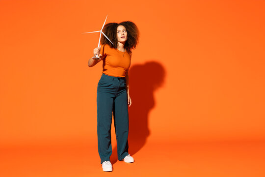Woman with wind turbine model in front of orange background