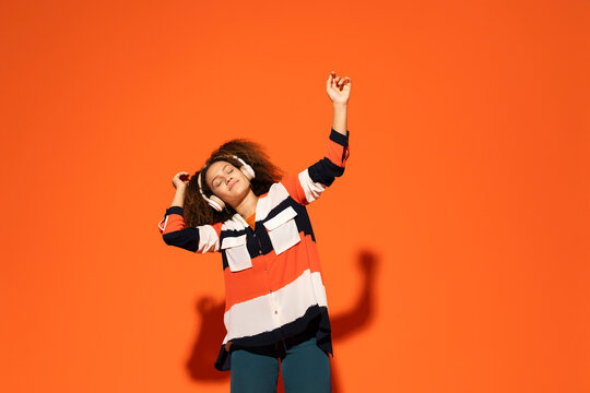 Woman with enjoying music in front of orange background