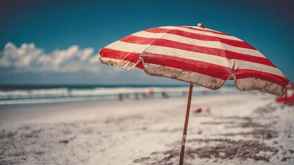 Red and white striped beach umbrella on a sandy beach with the ocean in the background. Concept Red and white striped beach umbrella on a sandy shore, Calm blue ocean backdrop