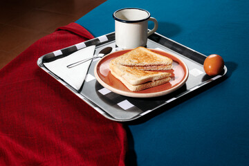 Breakfast with toast and coffee on a tray in bed with morning light