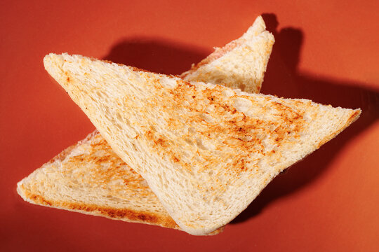 Two toasted sandwich triangles on orange background top view