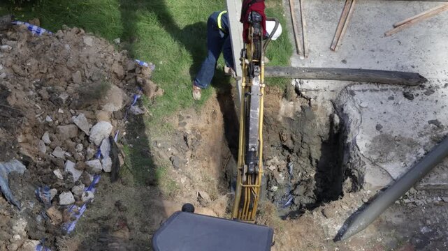 Excavation construction trench worker machinery digging foundation site soil safety urban jobsite as hydraulic excavator and digger repair utility lines, teamwork guides bucket with precision amid