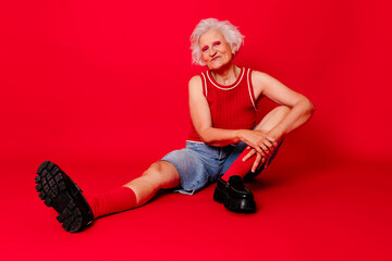 Woman in vibrant red outfit sitting against a red background, exuding energy and style