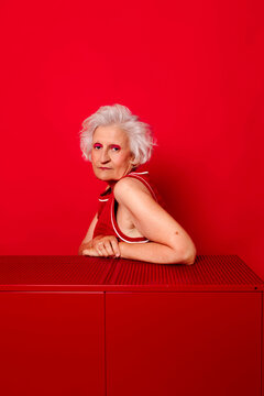 Woman with white hair posing against a red background