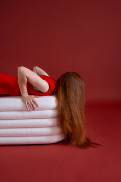 Girl in red dress lying on white couch with long hair covering face