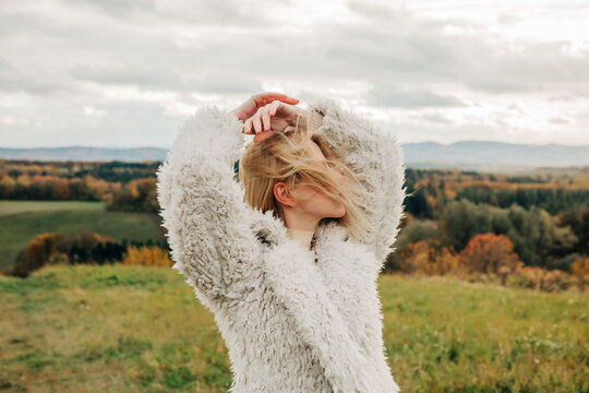 Stylish person in white sheep type jacket outdoors in autumn landscape