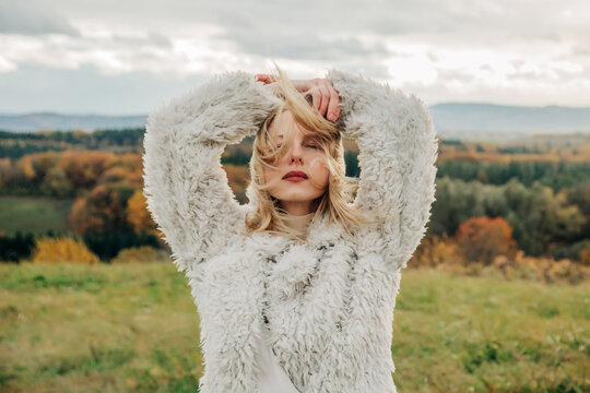 Fashionable person in white fluffy jacket standing outdoors in autumn