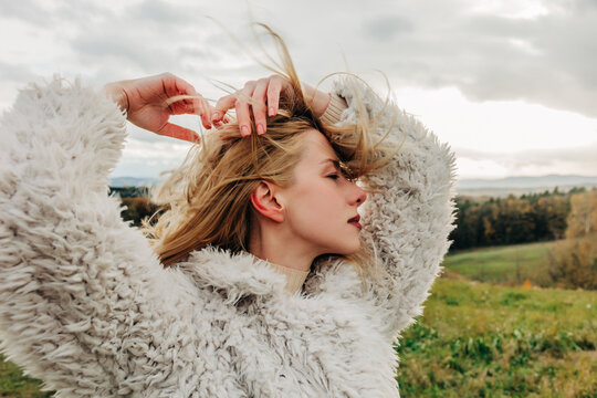 Fashionable woman in fluffy white jacket outdoors in autumn nature