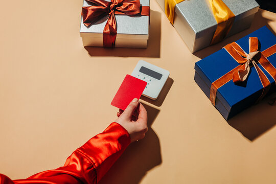 Woman in red shirt paying with credit card near gift boxes
